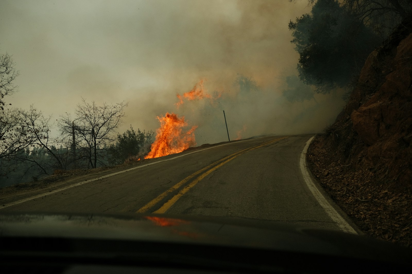 a fire is burning on the side of a road
