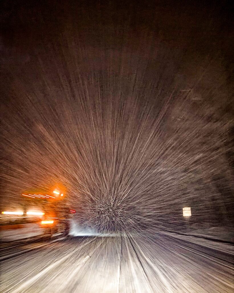 A blurry picture of a snow covered road at night